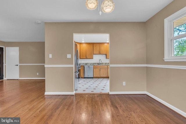 kitchen featuring light wood-type flooring, a chandelier, light countertops, baseboards, and appliances with stainless steel finishes