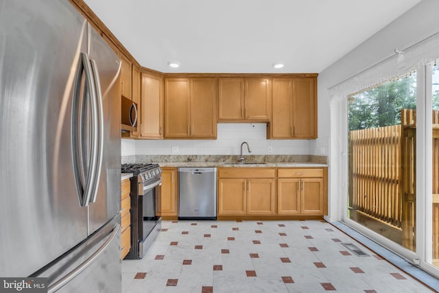 kitchen featuring a sink, light floors, light stone counters, visible vents, and appliances with stainless steel finishes