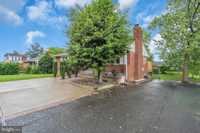 view of front facade featuring a chimney, a front yard, and brick siding