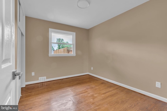 spare room with light wood-style floors, visible vents, and baseboards