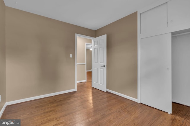 unfurnished bedroom with baseboards, a closet, and wood finished floors