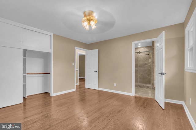 unfurnished bedroom featuring a closet, wood finished floors, ceiling fan, connected bathroom, and baseboards