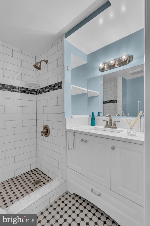 full bath featuring vanity, tile patterned flooring, and tiled shower