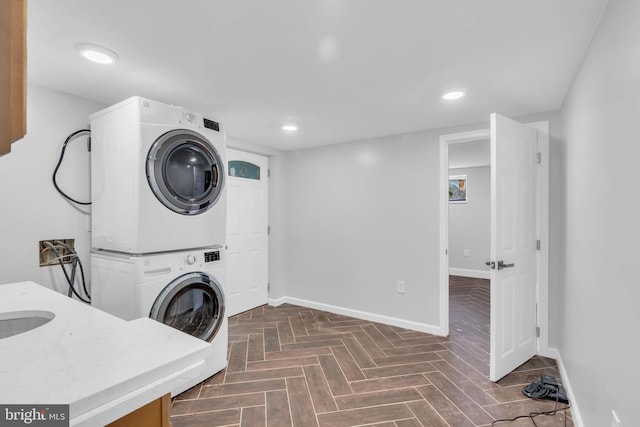 laundry area with baseboards, recessed lighting, laundry area, and stacked washer / dryer