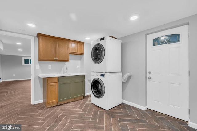 laundry area featuring baseboards, recessed lighting, stacked washer and clothes dryer, and cabinet space