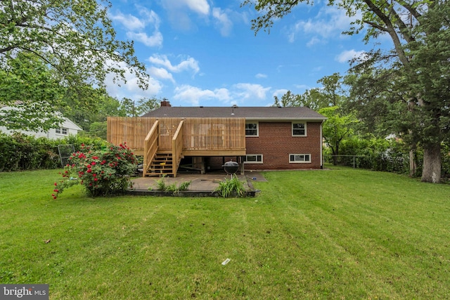 back of property with stairway, fence, brick siding, and a lawn