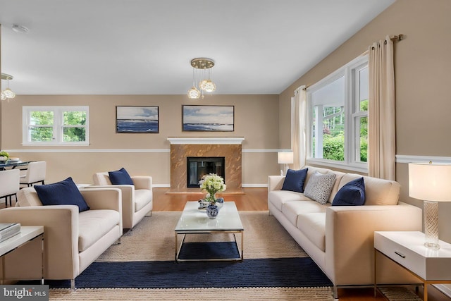 living room featuring baseboards, a high end fireplace, and wood finished floors