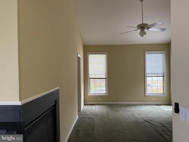unfurnished living room featuring carpet flooring, plenty of natural light, ceiling fan, and baseboards