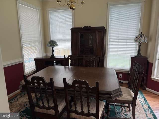 dining area with light wood-type flooring, baseboards, plenty of natural light, and a chandelier