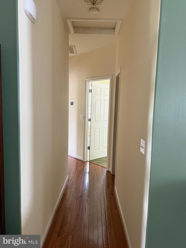 corridor with attic access, dark wood-style flooring, and baseboards