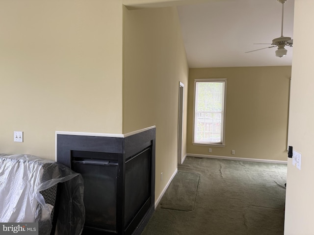 carpeted living area with ceiling fan, baseboards, and vaulted ceiling
