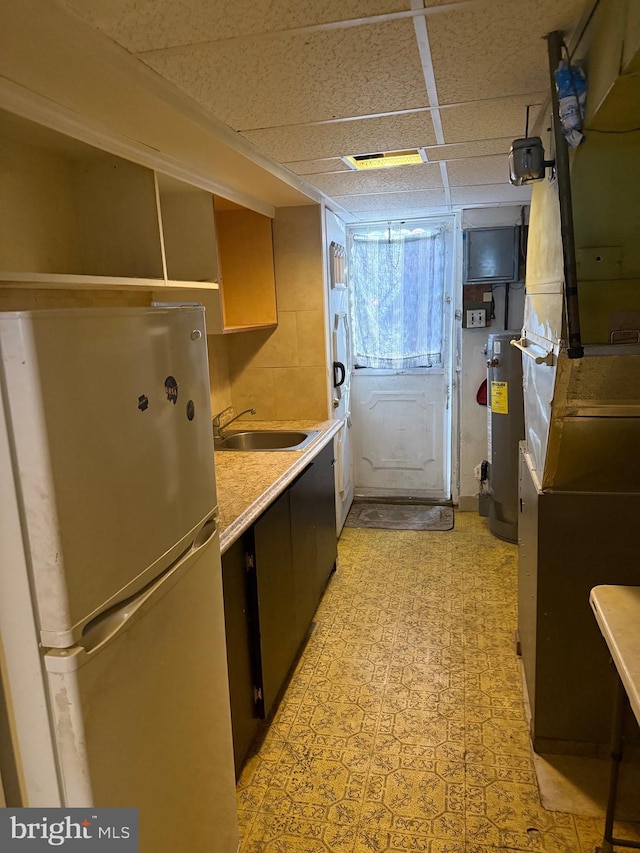 laundry area with light floors, water heater, and a sink
