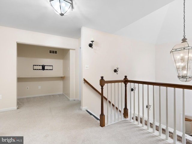 corridor featuring baseboards, an upstairs landing, visible vents, and carpet floors