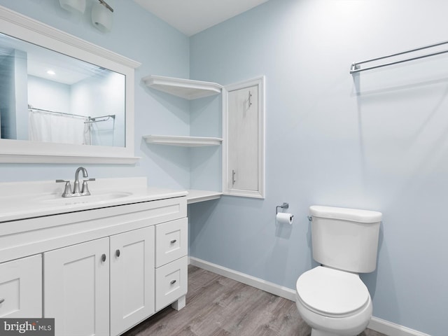 bathroom with vanity, toilet, baseboards, and wood finished floors