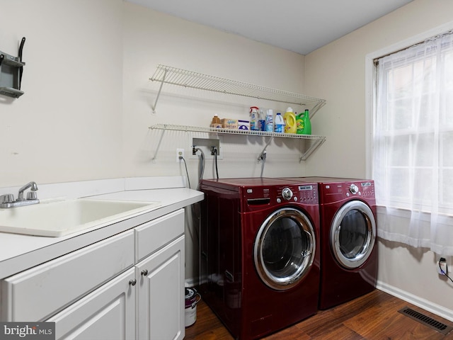 clothes washing area with washer and dryer, visible vents, a sink, dark wood-type flooring, and cabinet space