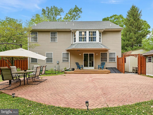 rear view of house with an outbuilding, fence, a patio, a deck, and a storage unit
