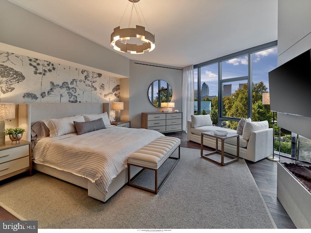bedroom with a chandelier, floor to ceiling windows, and wood finished floors