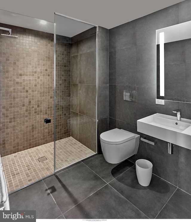 bathroom featuring a sink, tile walls, toilet, tile patterned flooring, and a walk in shower