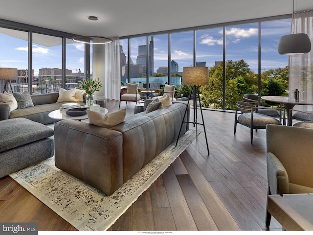 living area with a city view, expansive windows, and hardwood / wood-style floors