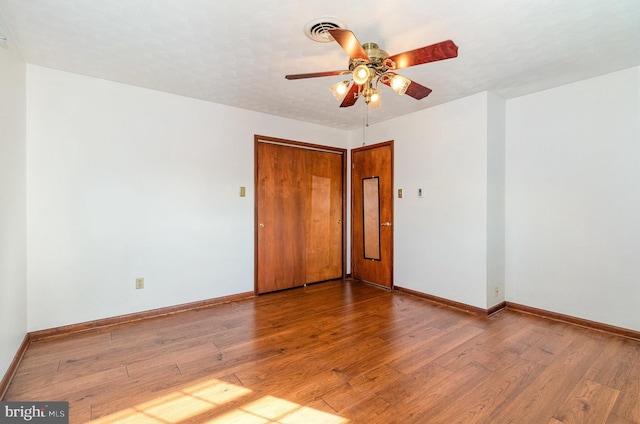 empty room featuring baseboards, a ceiling fan, visible vents, and wood finished floors