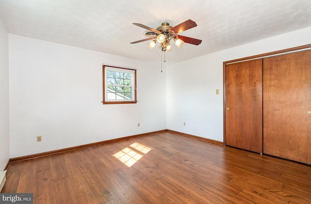 unfurnished bedroom with a closet, wood finished floors, and baseboards