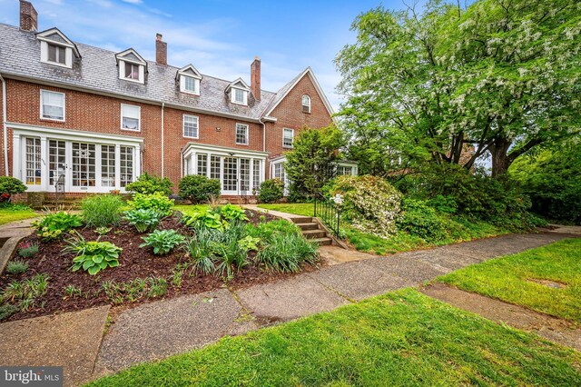 back of property with french doors, brick siding, and a chimney