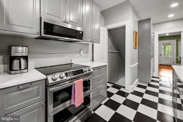 kitchen with recessed lighting, stainless steel appliances, gray cabinetry, light countertops, and dark floors