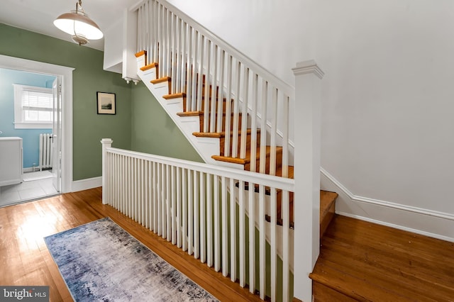 stairs featuring hardwood / wood-style flooring, radiator, and baseboards