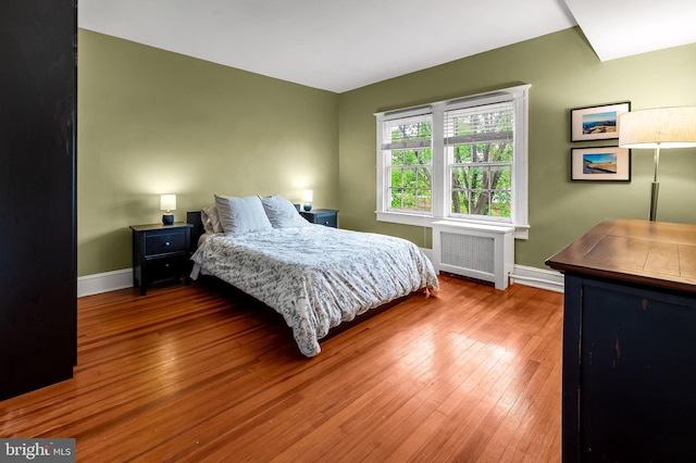 bedroom featuring radiator, baseboards, and hardwood / wood-style floors