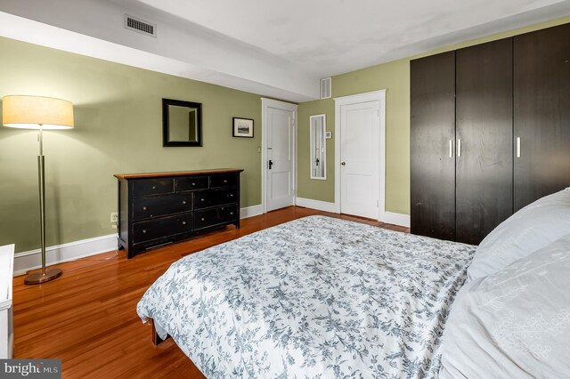 bedroom featuring baseboards, visible vents, and wood finished floors