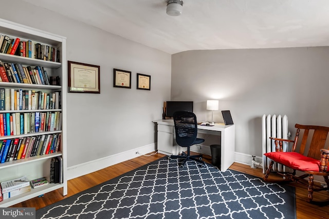 home office with vaulted ceiling, wood finished floors, baseboards, and radiator heating unit