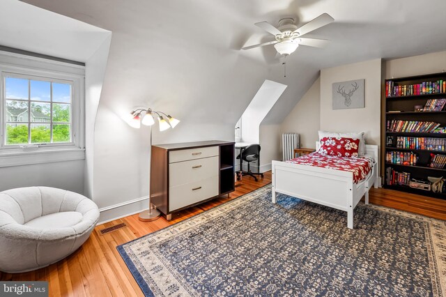 bedroom with lofted ceiling, baseboards, visible vents, and wood finished floors