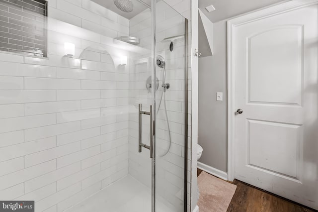 bathroom featuring a stall shower, baseboards, toilet, and wood finished floors