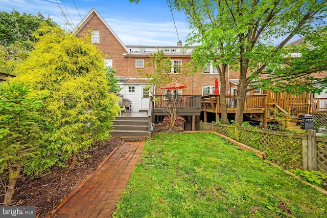 rear view of house with a lawn, a deck, and brick siding
