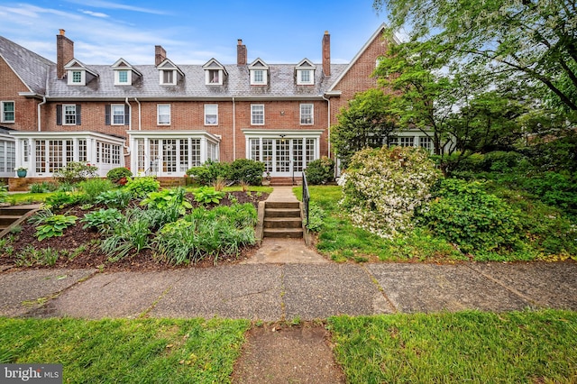 rear view of property with french doors, brick siding, and a chimney