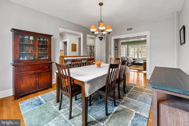 dining room featuring baseboards, an inviting chandelier, visible vents, and wood finished floors