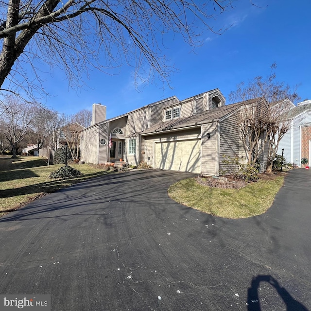 view of front of property with a chimney, driveway, and an attached garage