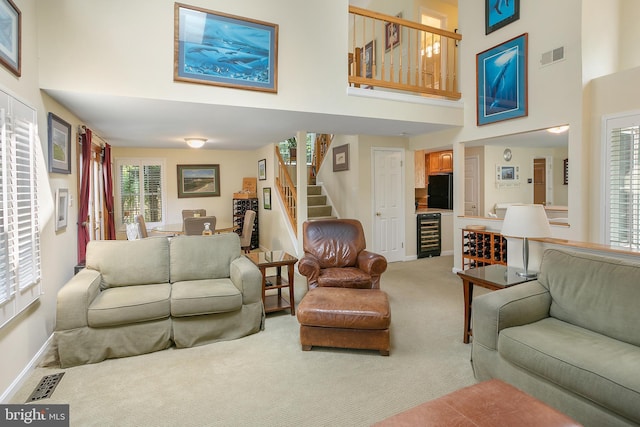 6018 Good Lion Ct, Alexandria, VA 22315 - living area featuring light colored carpet, a towering ceiling, stairs, baseboards, and wine cooler