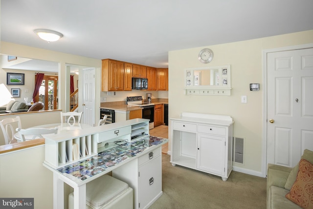 6018 Good Lion Ct, Alexandria, VA 22315 - kitchen with electric range, black microwave, light colored carpet, light countertops, and brown cabinets