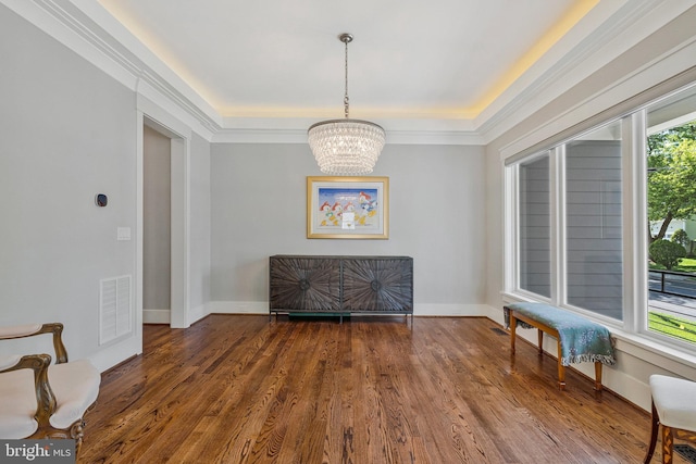 sitting room with a chandelier, wood finished floors, a raised ceiling, and baseboards