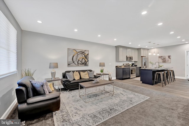 living room with recessed lighting, baseboards, and light wood-style flooring