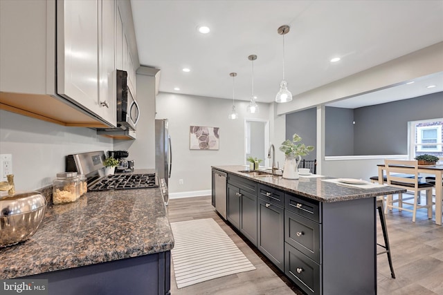 kitchen with a sink, stainless steel appliances, a kitchen breakfast bar, light wood-type flooring, and recessed lighting