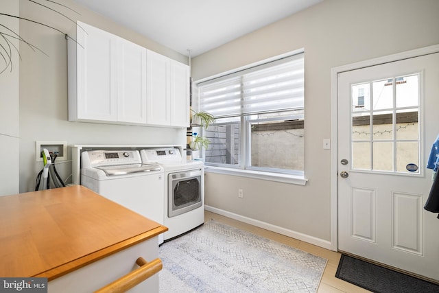 laundry area with washing machine and clothes dryer, baseboards, a healthy amount of sunlight, and cabinet space