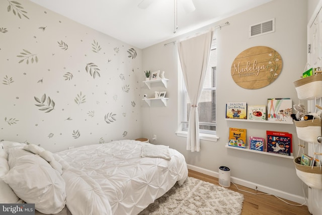 bedroom featuring baseboards, visible vents, a ceiling fan, and wood finished floors