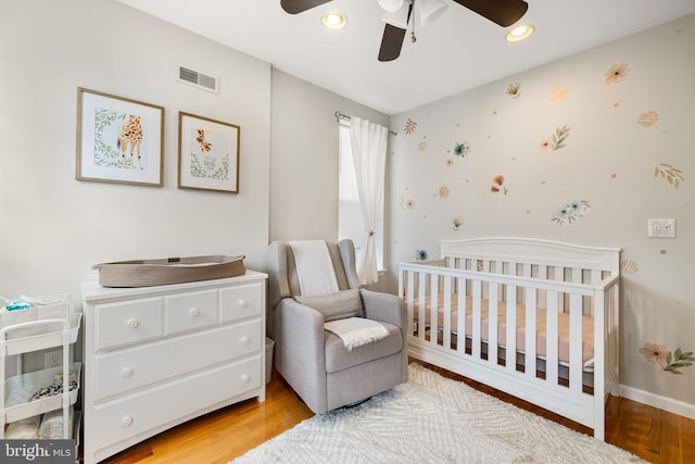 bedroom featuring a ceiling fan, a crib, visible vents, light wood-style floors, and recessed lighting