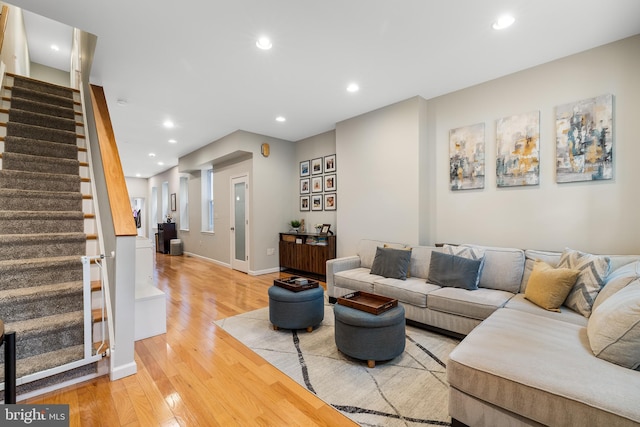 living area with baseboards, stairs, light wood-style flooring, and recessed lighting