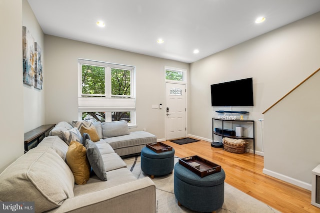 living room featuring baseboards, recessed lighting, light wood-type flooring, and plenty of natural light