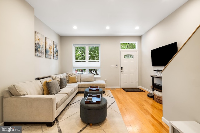 living area with baseboards, light wood finished floors, and recessed lighting