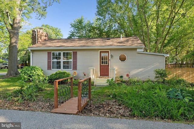 1215 Pine Ave, Shady Side, MD 20764 - view of front of house featuring a chimney, fence, and a shingled roof