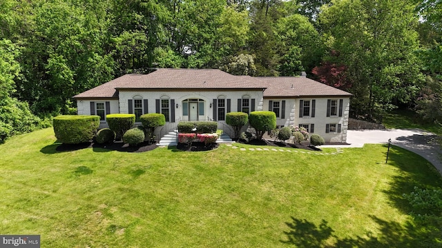 view of front facade featuring roof with shingles and a front yard